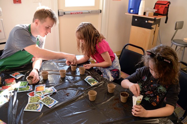 Child and Youth Program Assistant Peter Anderson helps 9-year-old Izzy Cherney and 8-year-old Soraya Khan plant cucumber and watermelon seeds Jan. 29 in the Osage School-Age Center science room at Fort Leavenworth, Kan. Photo by Prudence...
