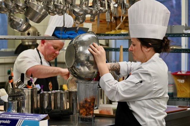 Commissaryman Chief Petty Officer Danielle Hughes (foreground) and Gunnery Sgt. Michael Watts, members of the U.S. Army Culinary Arts Team (USACAT), prepare competition dishes during a training session at the Originals Dining Facility on Panzer...