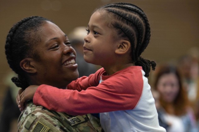 Army Staff Sgt. Erica Bradfield holds her child during a redeployment ceremony at Fort Stewart, Ga., Feb. 8, 2024. The event allows families to greet soldiers as soon as they get off the plane.