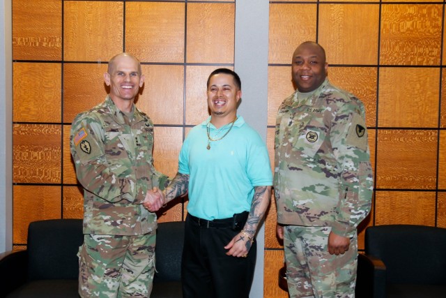 The commanding general of Installation Management Command, Lt. Gen. Omar J. Jones IV and Command Sgt. Maj. Jason R. Copeland present Christopher Ernest, lead human resources assistant, a coin on Feb. 28 for streamlining the Warrant Officer...