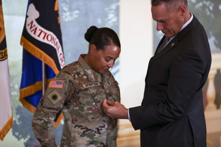 U.S. Army Brig. Gen. Robin Hoeflein, vice director of the Operations Directorate at the National Guard Bureau, looks on as her husband, Ray, affixes her rank to her uniform during a ceremony at Joint Base Myer-Henderson Hall, Virginia, where she was promoted to her current rank Feb. 29, 2024.  