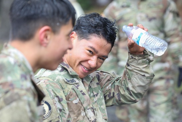 Cadet Gabriel Simpkins pours water on his head while smiling at Cadet Thomas Diaz after they both completed a confidence course at Camp Zama, Japan, March 12, 2024. Soldiers from the 35th Combat Sustainment Support Battalion hosted a field day to familiarize Zama Middle High School cadets with some aspects of Army life. 