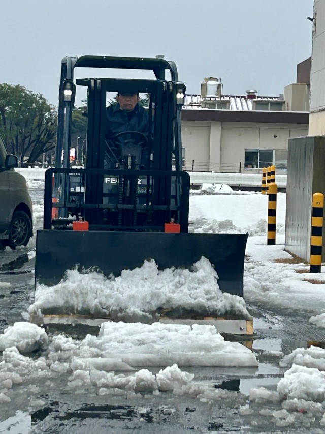 A base employee clears snow from a Camp Zama parking lot on Feb. 6, 2024, after heavy snow and slush covered the Kanto Plain. The community remained prepared for the event thanks to the hard work of a joint weather council. 