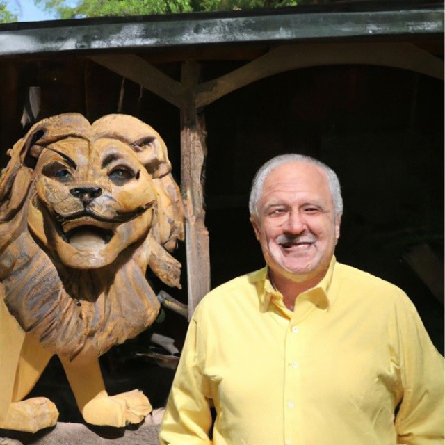 This image was created by DALL-E, OpenAI’s text-to-photo generator, using the prompt: 70-year-old man standing in front of a woodshop next to a realistic carving of a majestic lion’s face. Upon close inspection, you can tell the artificial...