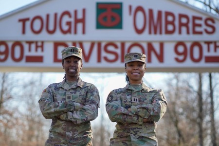 Captains Tamia (left) and Tamera (right) Grady pose under a 90th Sustainment Brigade monument on Camp Robinson, Ar. on February 23, 2024. The sisters were selected for company command and simultaneously commanded logistics units within the 90th Sustainment Brigade.