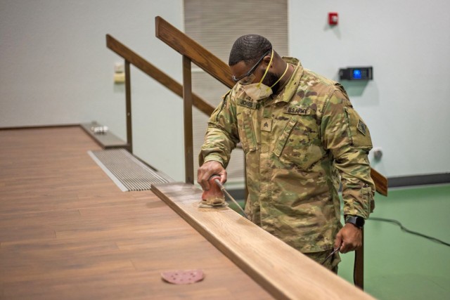 Engineer Advanced Leader Course student, Sgt. Brandon Jones, sands the ledge of the Nutter Field House stage during a two-day volunteer class project in early March that repaired and restored the wooden boards on the front of the stage. The seven...