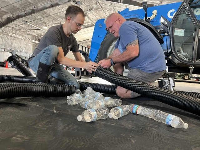 Brad Burden, biologist for the Adaptive and Integrative Management Team, and Tom Whittington, mobilization plans specialist for Fort Cavazos Directorate of Plans, Training, Mobilization and Security, place recycled plastic bottles into corrugated pipes for the floating island March 8, 2024. (U.S. Army photo by Christine Luciano, Fort Cavazos DPW Environmental)