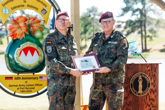 Deputy Commander German Army Aviation Command, Col. Bodo Schutte, presents a gift to Lt. Col. Michael Heger at Johnny Henderson Park in Enterprise, Ala. during the ceremony on March 28. 