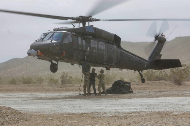 Soldiers sling load cargo for a UH-60A Blackhawk during an autonomous flight as part of persistent experimentation at Project Convergence - Capstone 4, Fort Irwin, Calif., on March 10, 2024. During Project Convergence in 2022 at Yuma Proving Ground, Ariz., a Blackhawk, using an autonomous system, performed three missions without a pilot. 