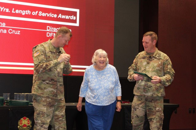 Donna Cruz, of Directorate of Family and Morale, Welfare and Recreation, is recognized for 45 years of service by Garrison Commander Col. Brian Cozine, right, and Command Sgt. Maj. Dylan Lemasters.