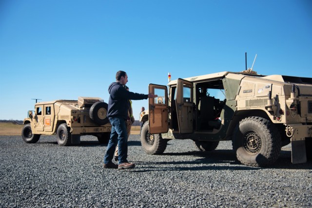 U.S. Army Aberdeen Test Center Test Officer, Alex Sanchez, explains aspects of one of the Tactical Hybrid Electric Vehicles to a visitor.