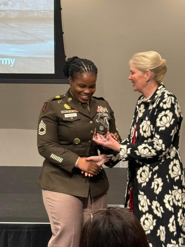 Two women shake hands while standing. 