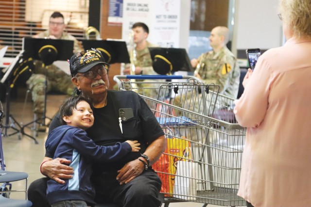 A man sitting and a child standing pose for a photo while hugging. 