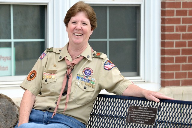 Carol Gersema, longtime supporter of Scouts BSA, smiles as friends and family take her photo on a bench dedicated to her for her contributions to Scouting during a surprise ceremony May 16, 2023, outside Patch Community Center at Fort Leavenworth,...