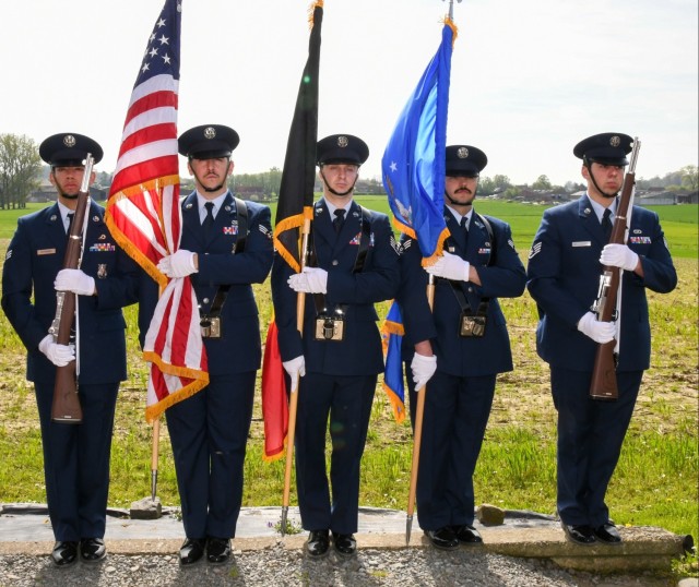 A color guard stands with the Belgian and American flag present. 