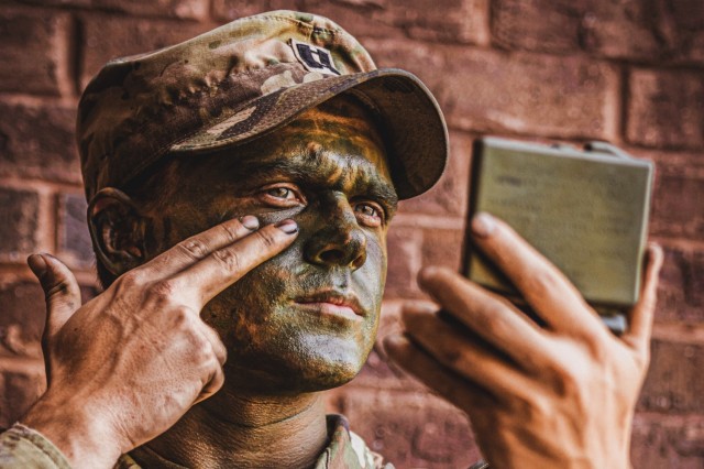 Capt. Moberly, the executive officer for Alpha Company, 2nd Battalion, 58th Infantry Regiment, 198th Infantry Brigade applies camouflage paint prior to executing a field training exercise.

Soldiers apply camouflage paint to their skin to enhance their concealment by disrupting the human silhouette and blending into the environment. This practice primarily aims to make them less detectable to the enemy. By applying irregular patterns, the paint reduces the risk of being spotted, as the human face is often recognizable even at a distance.
