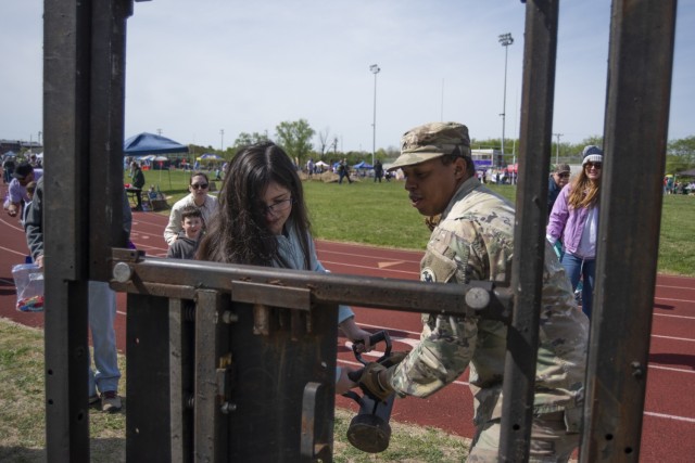 Twelve-year-old Olivia Kaiser attempts to breach a door with the help of Sgt. Labaron Wiggins, from Fort Leonard Wood’s Combat Engineer Skills Division, April 20 on Gerlach Field during one of the installation’s largest Month of the Military...