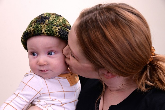 New Parent Support Program participant Jennifer Garrett kisses her 5-month-old son John after he received a crocheted baby hat made by volunteer Son Rodgers April 15, 2024, at the Resiliency Center at Fort Leavenworth, Kan. Photo by Prudence Siebert/Fort Leavenworth Lamp