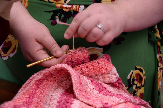 Volunteer Laura Benner finishes the edge of a crocheted blanket while delivering her handmade blankets to the New Parent Support Program for distribution to families with babies April 15, 2024, at the Resiliency Center at Fort Leavenworth, Kan. Photo by Prudence Siebert/Fort Leavenworth Lamp