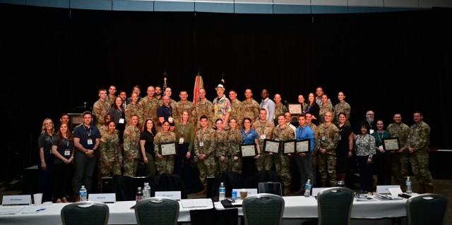 The Army recognized its top-notch Holistic Health and Fitness practitioners during its H2F Symposium April 30, 2024 at the Hampton Roads Convention Center in Hampton, Va. Sgt. Maj. of the Army Michael Weimer, the keynote speaker for the event, and Maj. Gen. John Kline, U.S. Army Center for Initial Military Training Command and host of the event, stand with some of the H2F programs who were recognized during the event. (U.S. Army photo by Jean Wines)