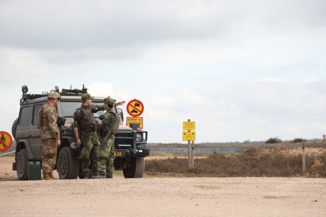 U.S. Army Sgt. Logan Cody, a motor transport operator assigned to the Washington-based 1214th Forward Support Company, 1st Battalion, 214th Field Artillery Regiment, 648th Maneuver Enhancement Brigade speaks with Swedish Army Elias Gimburg and...