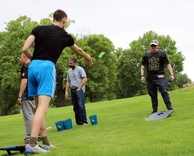 Pfc. Nicholas Jones, Headquarters and Headquarters Company, U.S. Disciplinary Barracks Battalion (Corrections), tosses a beanbag toward a cornhole board manned by Sgt. 1st Class Randall Peaslee, HHC, Army Corrections Command, at one of the...