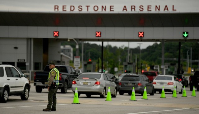 Aaron Hanson, a game warden with U.S. Fish and Wildlife, directs drivers into the inspection lanes a few hundred yards north of Gate 9 as Redstone security forces, working with the Madison County Sheriff’s Office, search vehicles entering the...