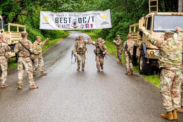 U.S. Army Staff Sgt. Joshua Katz (left) and Capt. Patrick Thomas (right), assigned to 181st Infantry Brigade, triumphantly cross the finish line ending the timed ruck at the annual Gen. Omar N. Bradley Best Observer Coach Trainer (OC/T)...