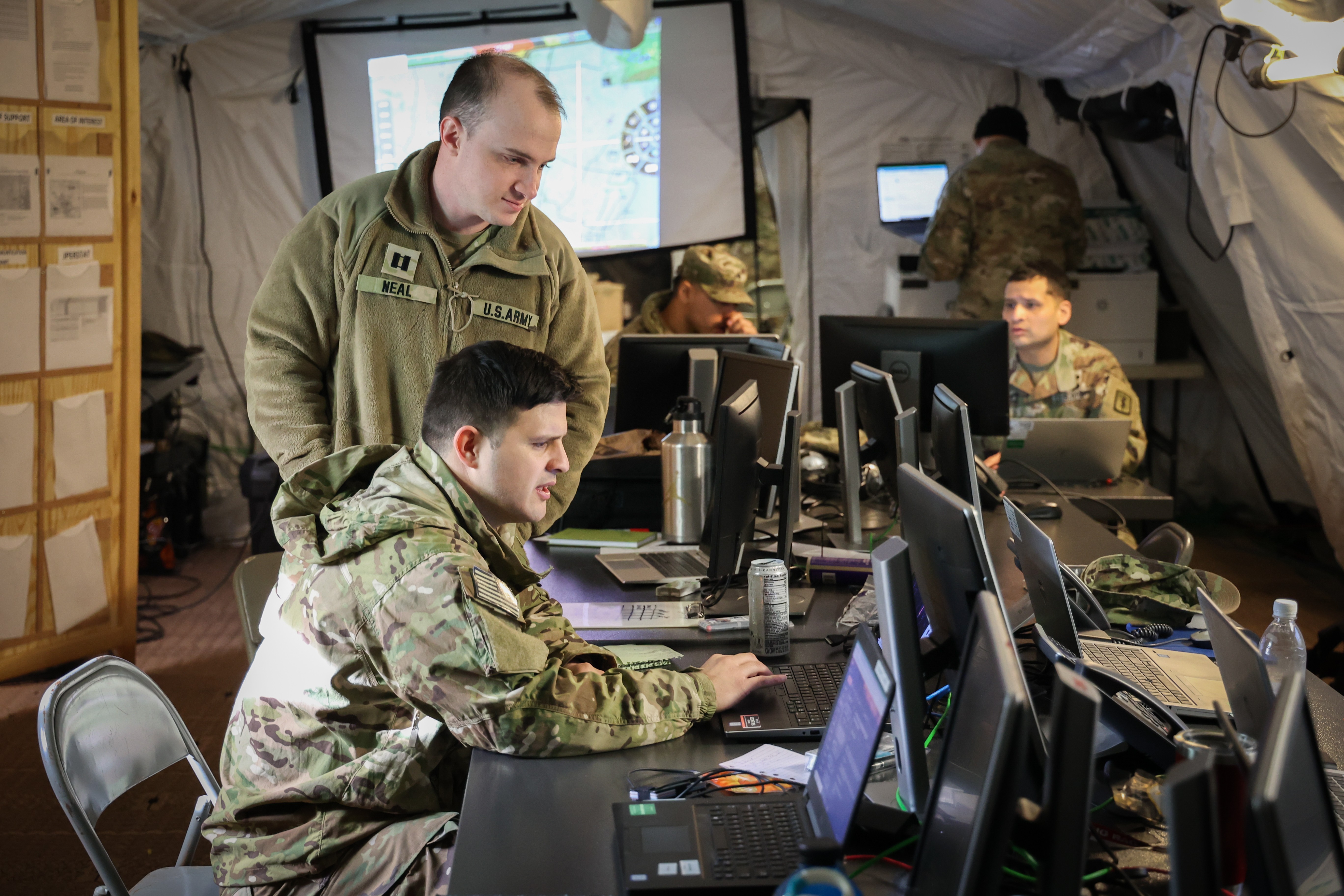 U.S. Army Capt. Craig Neal, a chemical, biological, radiological and nuclear officer at 30th Medical Brigade (top), helps Capt. Julio Rodriguez, a health services plans, operations, intelligence, security and training officer at 30th Medical Brigade (bottom) on his computer while trying to find documentation for a mission during a Command Post Exercise on Rhine Ordnance Barracks, Kaiserslautern, Germany on March 16, 2023. The Command Post Exercise was held to prepare junior Soldiers and senior leaders for Defender ‘23 using real world scenarios. 