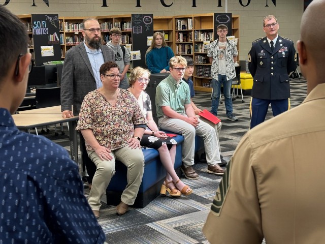 Jacob Mills and Liam Fedak, surrounded by their families, listen to Staff Sgt. Rocky Wilson, as he explains why he wanted to be a part of the day’s ceremony. (U.S. Army photo by Anne Bowman)
