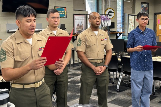 (from left) Gunnery Sgt. Damian Arredondo, a Cyber Instructor with the U.S. Army Cyber Center of Excellence, reads the Letter of Appreciation being presented to Liam Fedak and Jacob Mills, 10th grade high school students and friends of his son,...