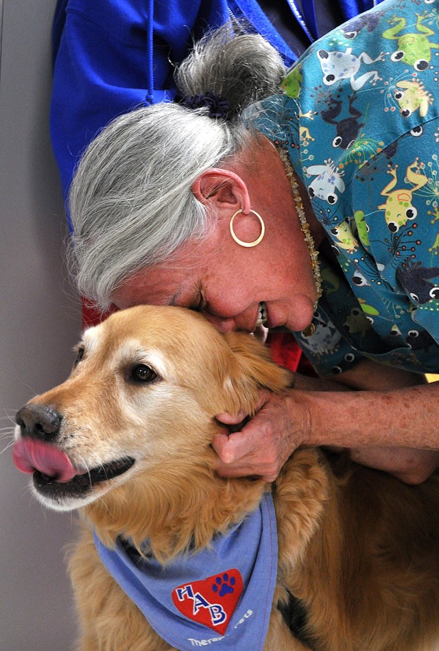 Optometric Technician Pat McLaughlin snuggles with Fort Leavenworth Human Animal Bond member Ruie Gibson's dog, Titan, during a visit Feb. 27, 2014, at Munson Army Health Center, Fort Leavenworth, Kansas. HAB teams, comprised of dogs with their...