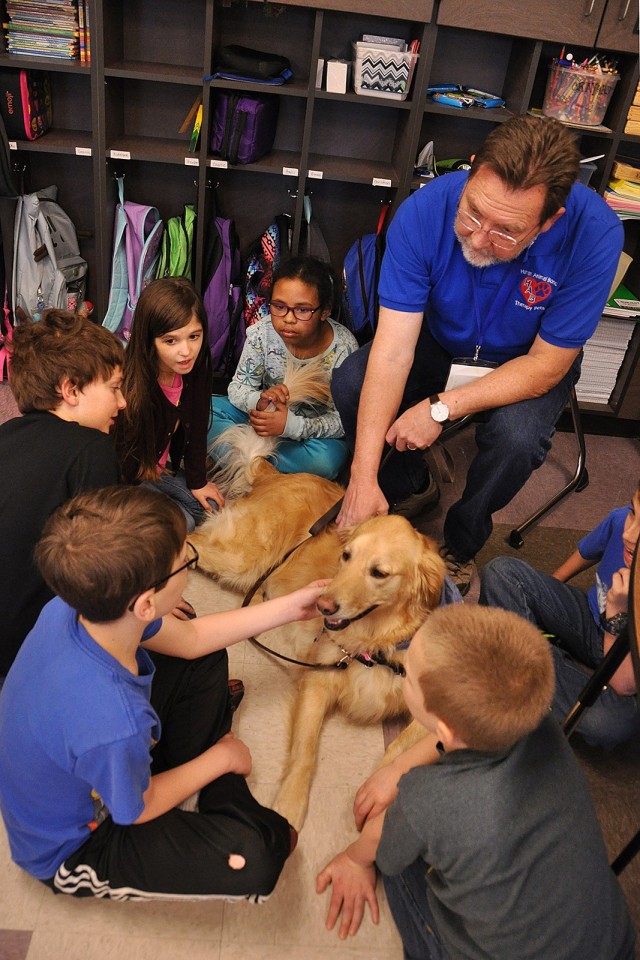 Third-grade students, including Mark Goodman, Jack Miller, Kiersten Kessler and Jasmine Day, visit with Human Animal Bond volunteer Jim Iverson and his golden retriever, Mia, April 6, 2017, at Henry Leavenworth Elementary School in Leavenworth,...