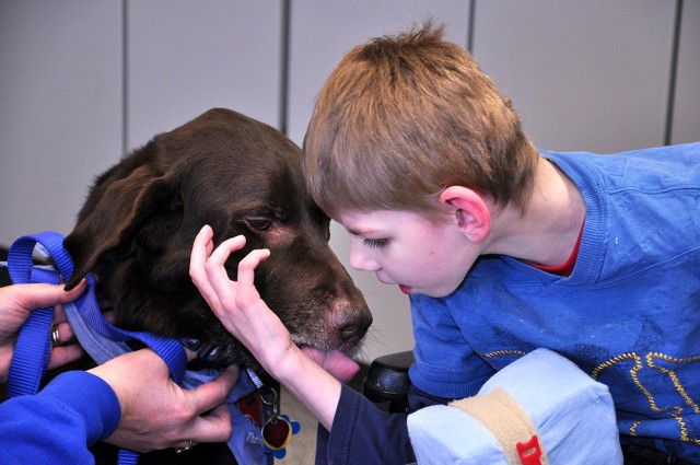 Eight-year-old Austin Vossmer finds a way to communicate that he wants a kiss from Tanya Berg's Labrador retriever, Jack, during a Human Animal Bond pet therapy group visit to the life-skills class March 4, 2014, at MacArthur Elementary School on...