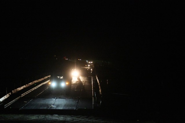 Michigan National Guard Engineers of the 1437th Multi-Role Bridge Company worked through the night to unload trucks carrying boats and bridge sections and successfully pieced together a bridge across the Mississippi River during training on Camp...
