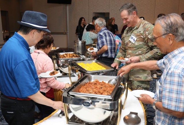 Lt. Col. Damon Saxton, right, the U.S. Army Garrison Japan chaplain, and members of the Japan-America Society of Central Kanagawa enjoy a buffet of food items from Virginia and Indiana during a “State Day” event at Camp Zama, Japan, June 20, 2024. 