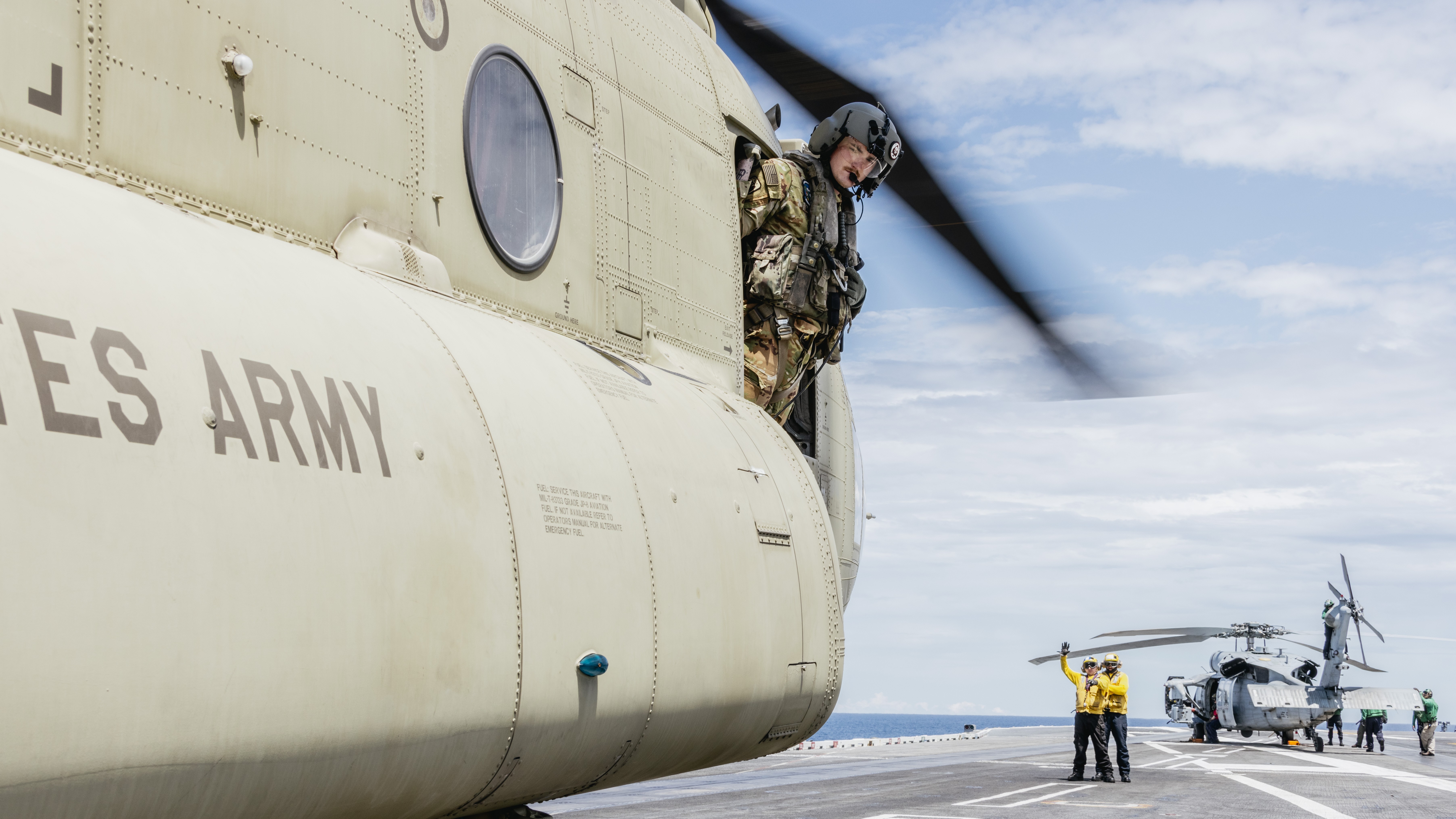 U.S. Army Sgt. Quinlan J. Merrill, from Rapid City, South Dakota, assigned to the 1-228th Aviation Regiment, leans out the gunner’s window of an CH-47 Chinook on the flight deck of Nimitz-class aircraft carrier USS George Washington (CVN 73)...