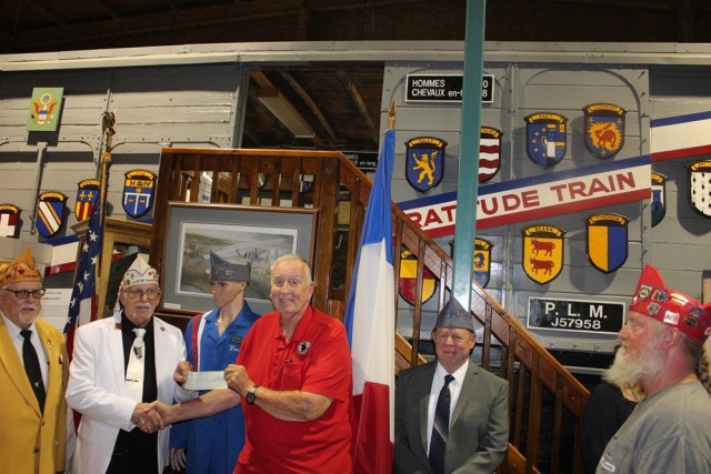 Paul Vishaway, Chef de Gare or state commander for Grande Du Alabama, presents a $250 check to U.S. Veterans Memorial Museum Director Randy Withrow for upkeep of the vintage French boxcar at the museum. From left are John Schnatz, boxcar director;...