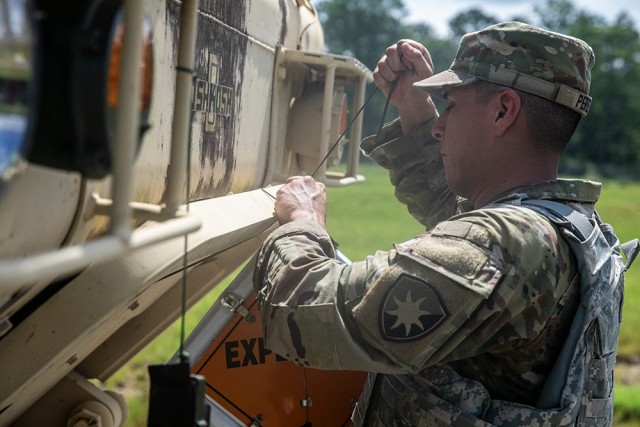 Army Sgt. Sergio Perez, an automatic logistics operator assigned to the 50th Regional Support Group, applies an “EXPLOSIVE” sign to a M977A4 HEMTT cargo transporter in preparation for a convoy that will transport ammunition from an ammunition...