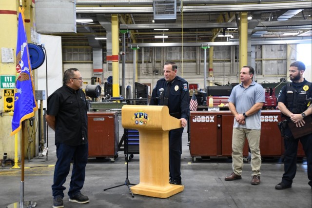 Yuma Police Department (YPD) Chief Thomas Garrity (center) speaks at a ceremony honoring Rick Ramirez, team lead for wheeled vehicles at U.S. Army Yuma Proving Ground’s Maintenance Branch (left) on July 25, 2024 as Yuma Mayor Douglas J. Nicholls...