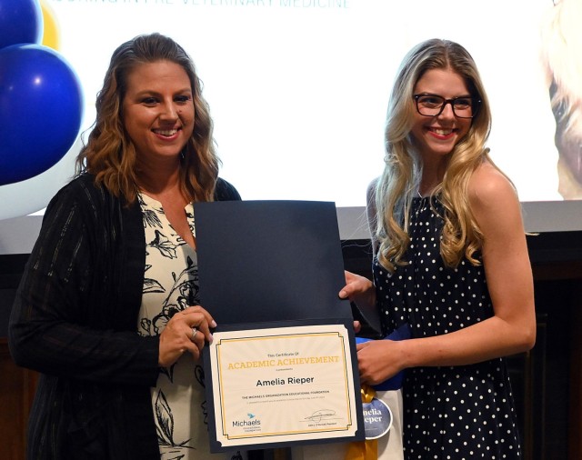 Frontier Heritage Communities Assistant Community Director Leigh Brown congratulates Amelia Rieper on receiving a scholarship from The Michaels Organization Educational Foundation during a scholarship luncheon July 25, 2024, at the Frontier...