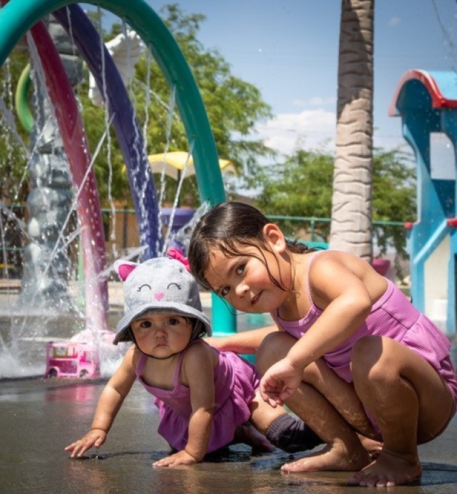 Military children, one curious the other poses for the camera, as they beat the heat by enjoying the Fort Irwin Splash Park on 2nd Street; one of the several R2 facilities available on Fort Irwin.