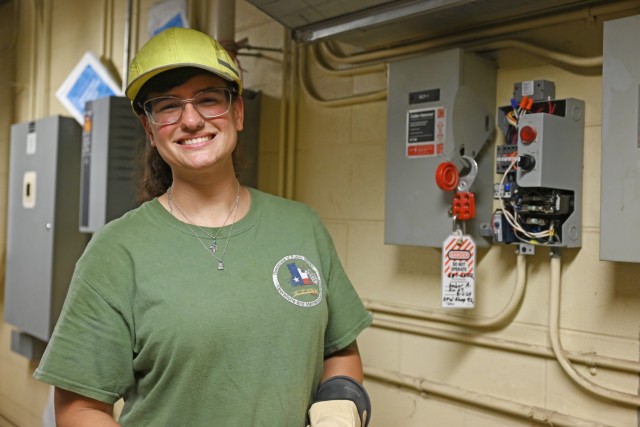 A woman standing poses for a photo by electrical circuit box.