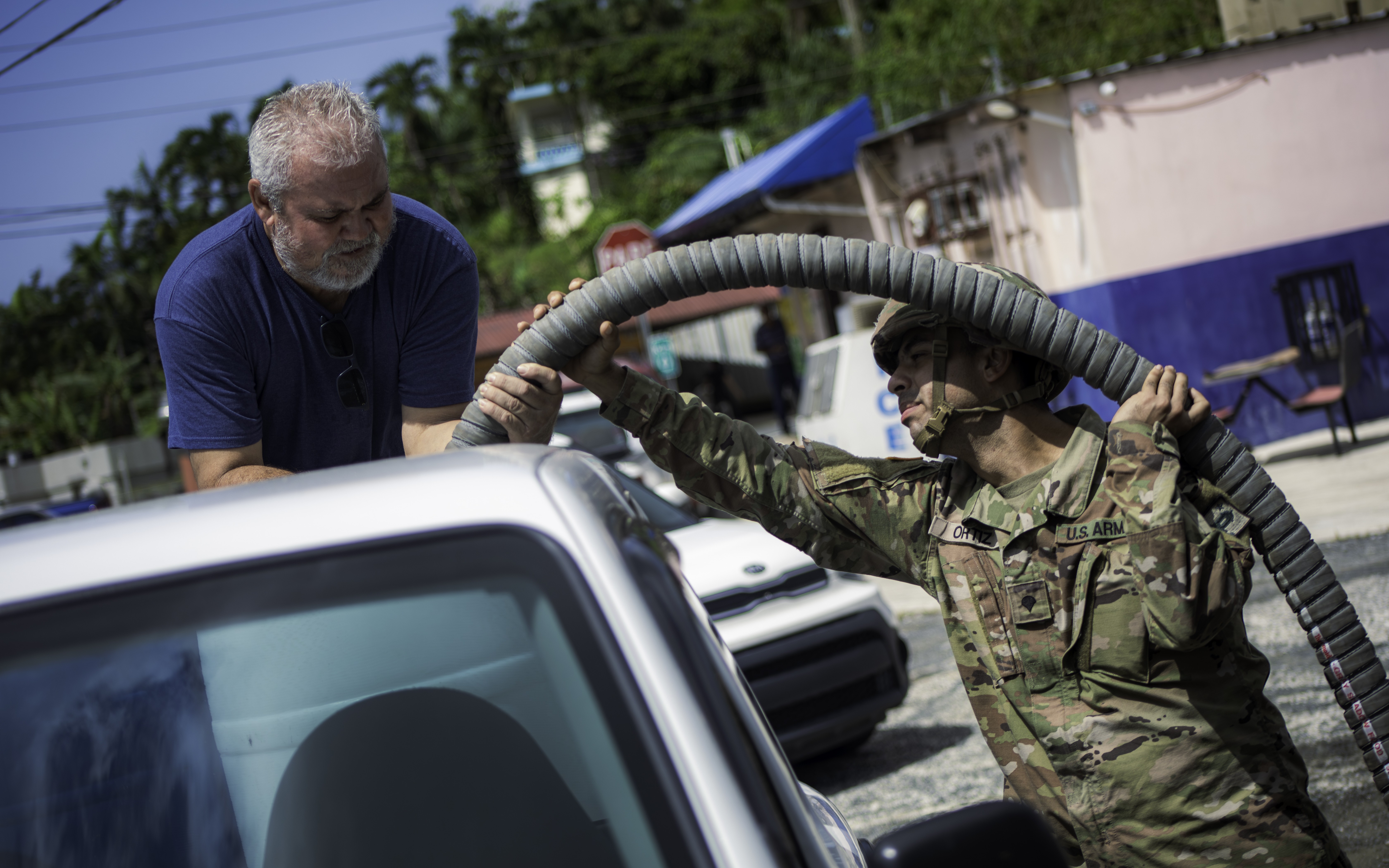 U.S. Army Spc. Jonathan Ortiz Savola assigned to the 219th Quartermaster Detachment, 191st Regional Support Group, Puerto Rico Army National Guard, helps a civilian fill up his water container during state active-duty operations at Cidra, Puerto...