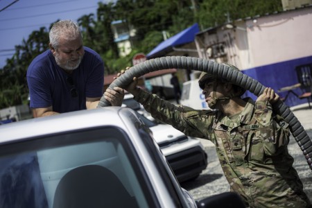 U.S. Army Spc. Jonathan Ortiz Savola assigned to the 219th Quartermaster Detachment, 191st Regional Support Group, Puerto Rico Army National Guard, helps a civilian fill up his water container during state active-duty operations at Cidra, Puerto...