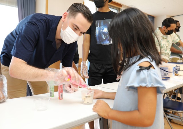 Staff Sergeant Brian Hanson (left) of the 38th Air Defense Artillery Brigade helps sprinkle a Sagamihara Minami Children's Home resident's cup of ice cream during an exchange event Aug. 14 in Sagamihara, Japan.