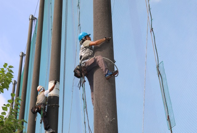 Contractors prepare to repair a net on the driving range at Camp Zama Golf Course in Japan on August 19, 2024. The course is currently undergoing extensive repairs to the mesh netting as part of ongoing efforts to keep balls within the course perimeter.