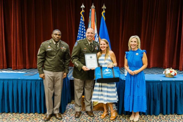 Col. John P. Miller III, Fort Novosel garrison commander, Fort Novosel garrison Command Sgt. Maj. Garry Williams, and Mrs. Mollie Miller present Jessica Merrill with a volunteer of the quarter award at The Landing on Aug. 27, 2024.