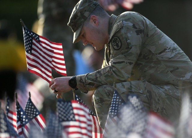 Staff Sgt. Steven Masterton places flags in the ground Monday as Soldiers and staff members from Fox Army Health Center place 492 American flags in the front of Fox during a flag-laying ceremony for National Suicide Prevention Month.