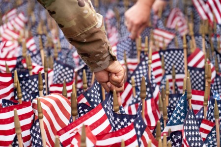 Service members, families and community members come together to honor the memory of Sept. 11, 2001, by placing flags at the Rock Island Arsenal 9/11 memorial. Each flag is carefully positioned in the ground behind the brick replica of the World...